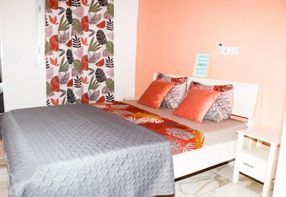 een slaapkamer met een bed met oranje kussens bij Le relax in Bonamoussadi