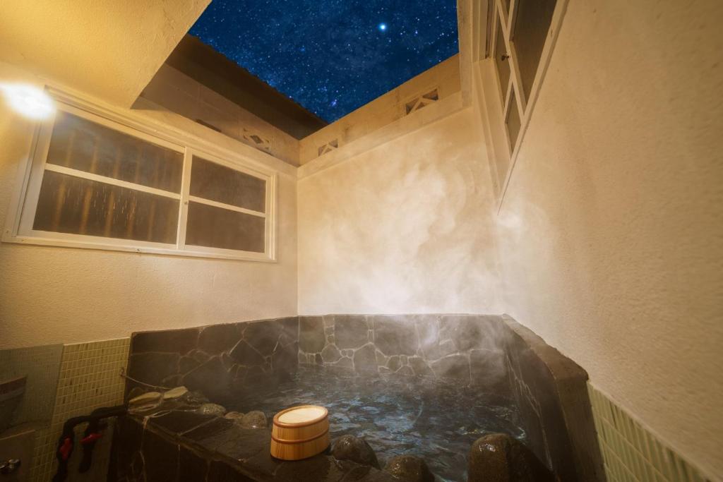 a bath tub in a room with a starry sky at Yufuin Ekimae Yado Kachofugetsu - Vacation STAY 88189v in Yufuin