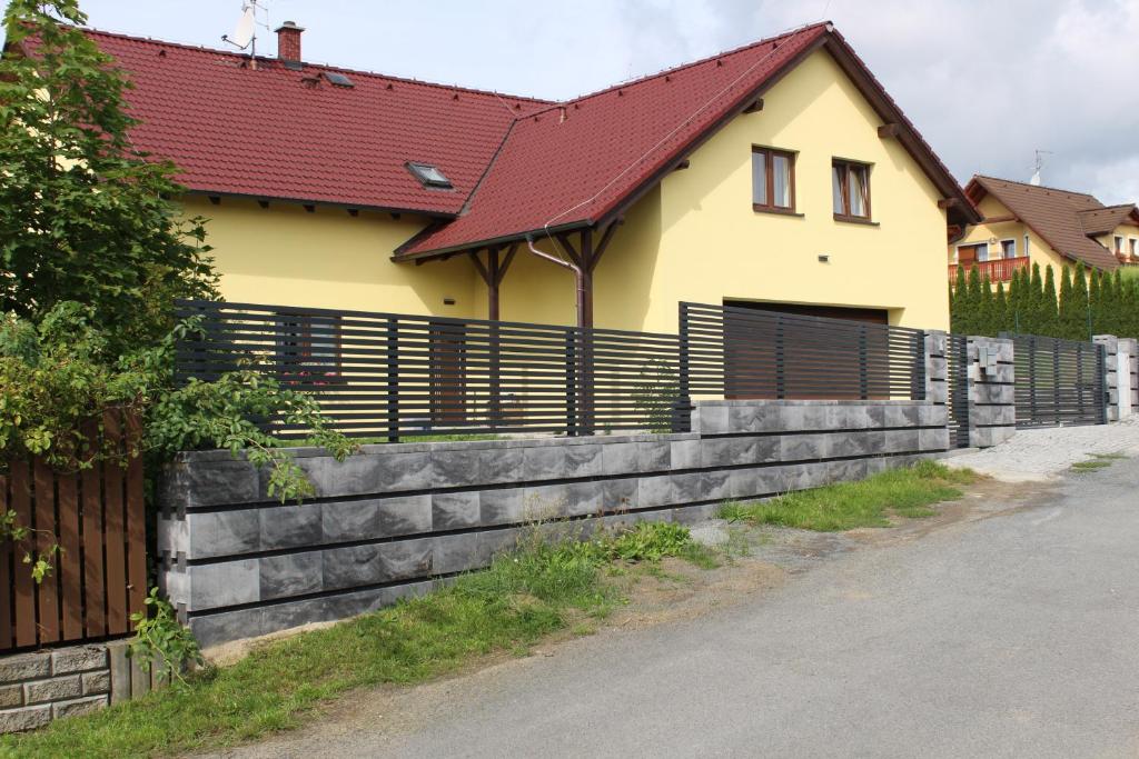 a yellow house with a wooden fence next to a road at Apartmán 2023 in Stříbro