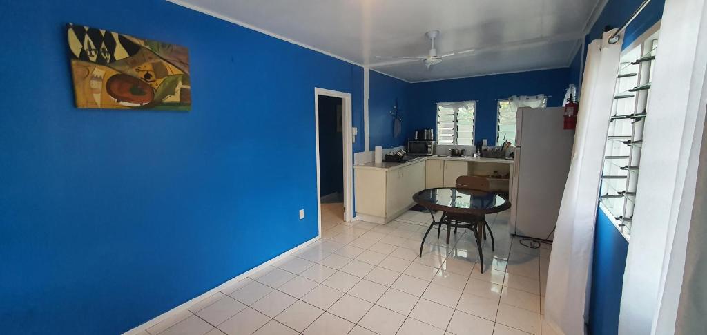 a blue room with a table and a kitchen at Lynn's Getaway Guest House in Apia