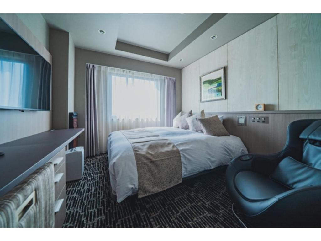 Habitación de hotel con cama y silla en Hotel Grand View Takasaki - Vacation STAY 55422v en Takasaki