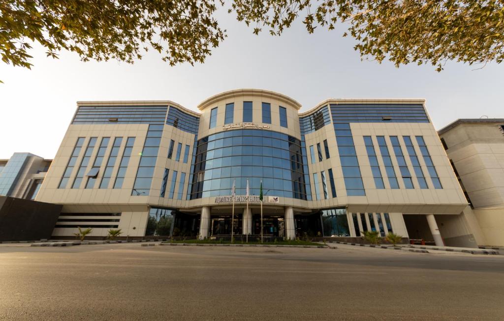 a large office building with a parking lot in front of it at Admire Apart' Hotel in Riyadh