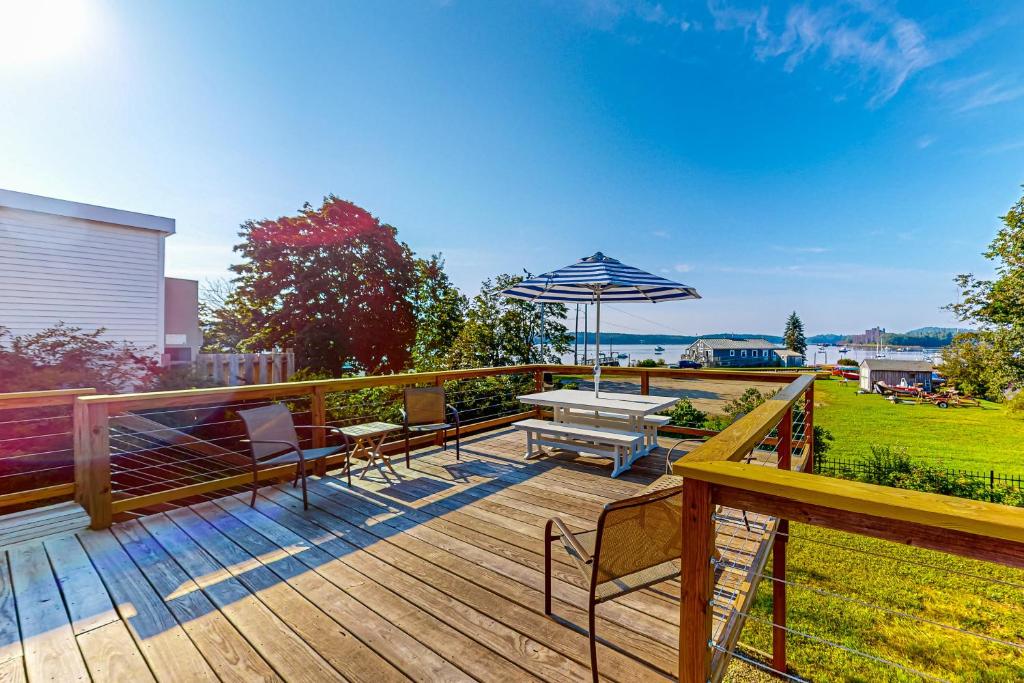 una terraza de madera con mesa de picnic y sombrilla en Topgallant en Wiscasset