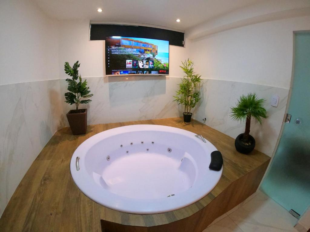 uma grande banheira na casa de banho com vasos de plantas em TH 101 - Flat com Banheira de Hidromassagem em Governador Valadares