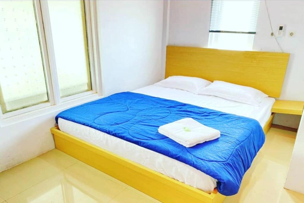 1 dormitorio con 1 cama con manta azul y 2 ventanas en OYO 93052 Batodupi Guesthouse Syariah, 