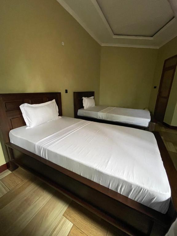 1 dormitorio con 2 camas con sábanas blancas en Skill forest lodge en Arusha
