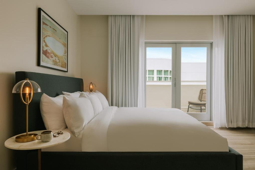 a bedroom with a large white bed and a balcony at Sonder The Deco in Miami Beach