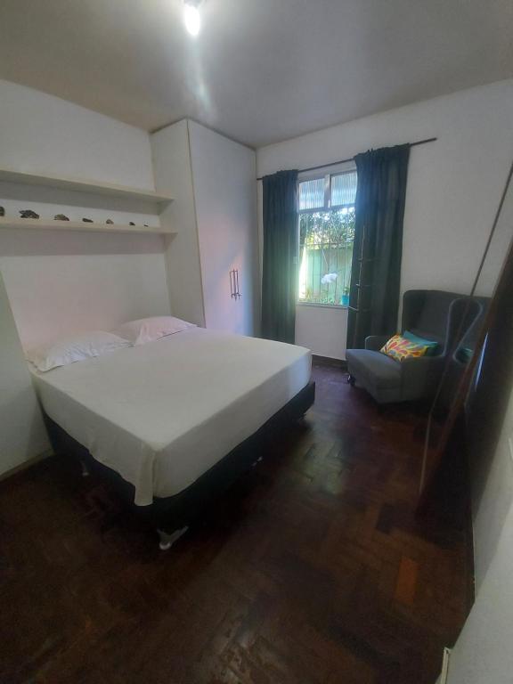 a bedroom with a bed and a chair and a window at Quarto tranquilo e familiar no leblon - Quiet family room in leblon in Rio de Janeiro