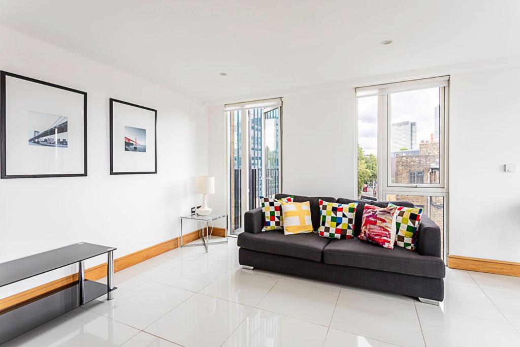 a living room with a black couch and some windows at Convenient Euston London Apartment in London