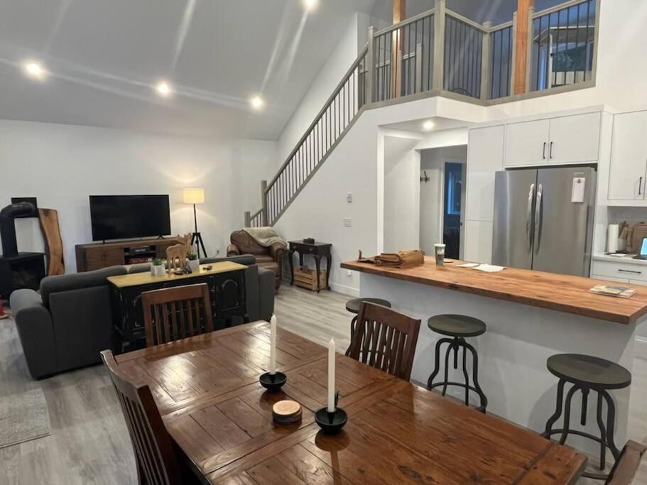 ein Wohnzimmer mit einem Holztisch und einer Küche in der Unterkunft Stunning 5-bed Retreat in Sunshine Valley in Sunshine Valley