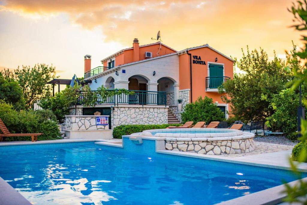 uma casa com piscina em frente a uma casa em Vila Bonita em Klek