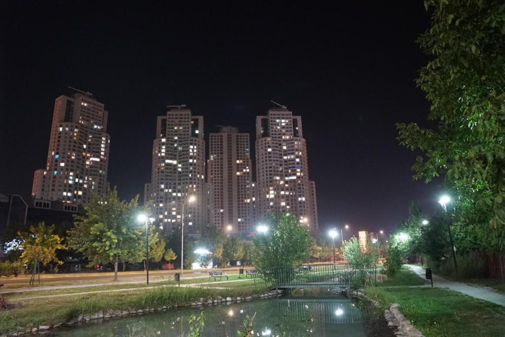 une vue sur la ville la nuit avec un étang dans un parc dans l'établissement Skopje Sky City 19th Floor Twin Apartments with Indoor Pool & Spa & Fitness Including in Price, à Skopje