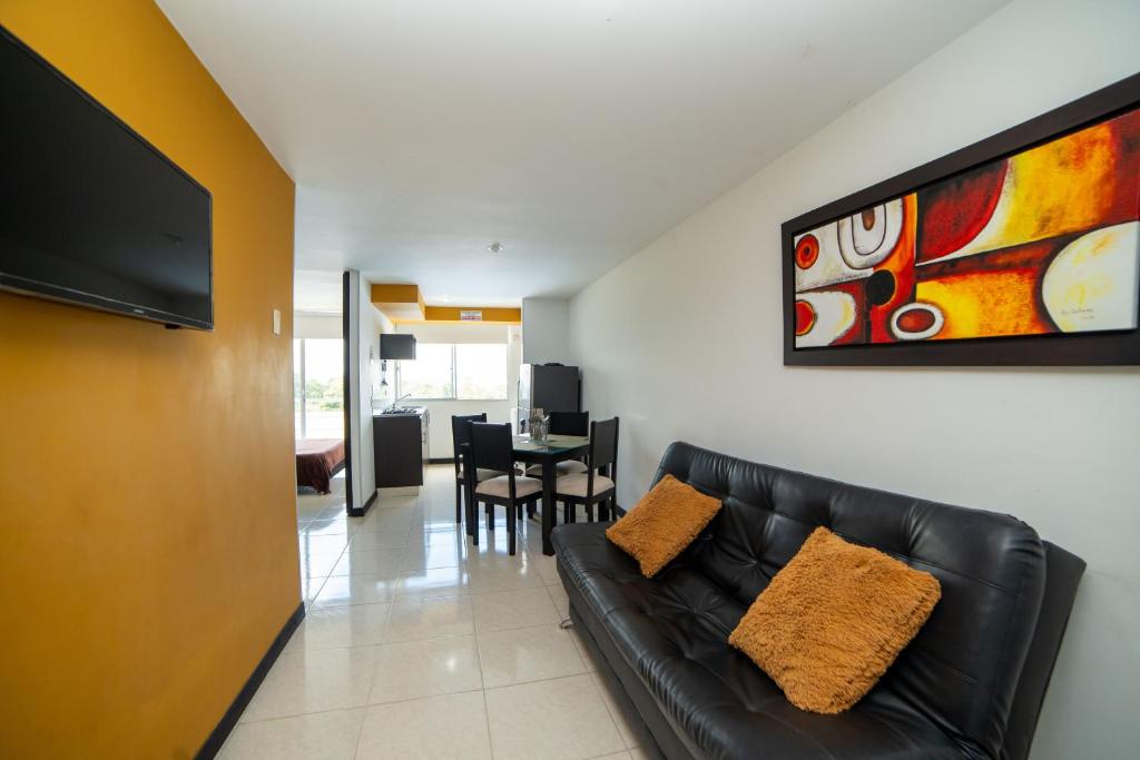 uma sala de estar com um sofá de couro preto e uma mesa em Apartamento con parqueadero, piscinas y wifi a 5 min del parque del café em Montenegro