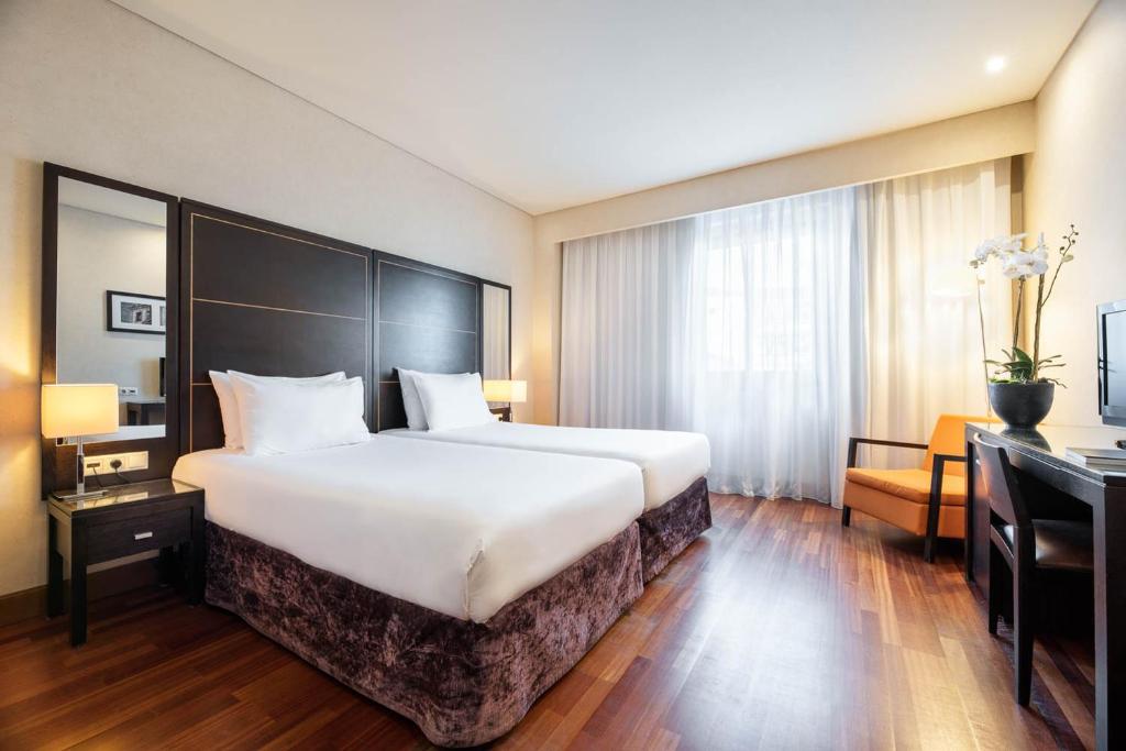 um quarto de hotel com uma cama grande e uma secretária em Eurostars das Artes no Porto