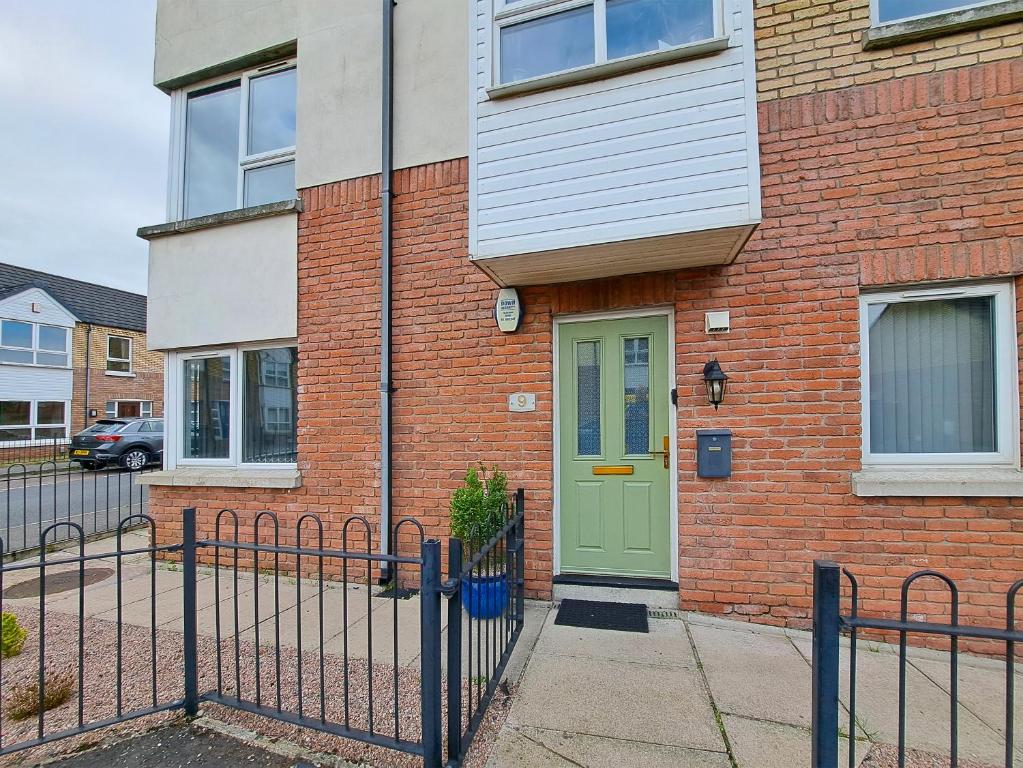 a brick house with a green door and a fence at Kings Lodge One Bed Apartment in Belfast