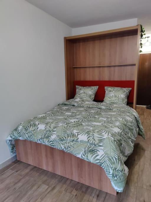 une chambre avec un grand lit avec une tête de lit en bois dans l'établissement *Le Super Land* Parking Privé * Cadre verdoyant*, à La Grande Motte