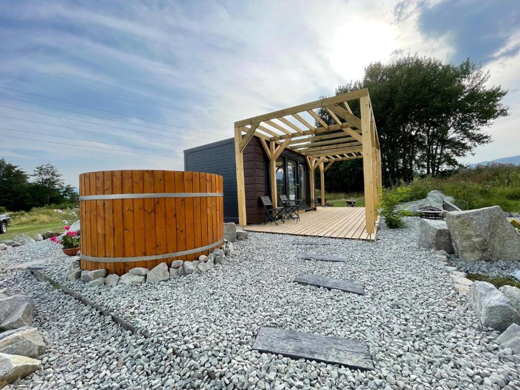 a building with a wooden pergola on a gravel field at Tiny House with Mountain Views in Turany