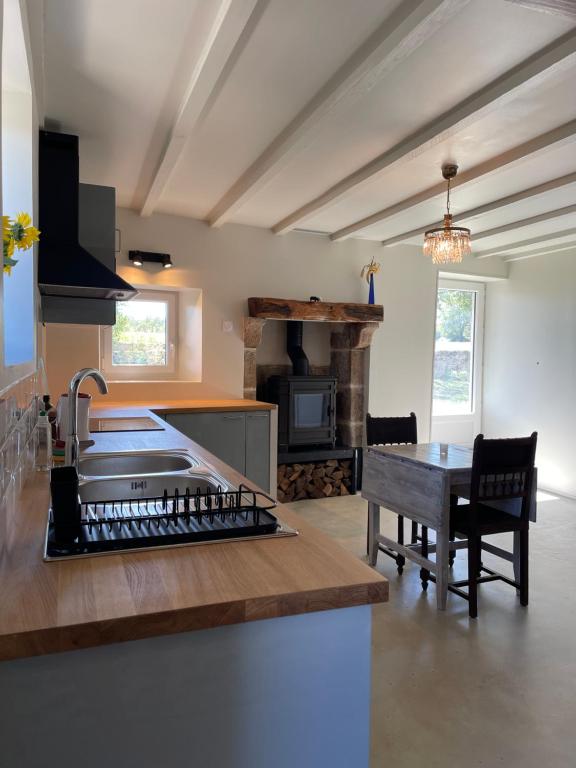 a kitchen with a sink and a table and a stove at Belle vue in Saint-Silvain-Bas-le-Roc