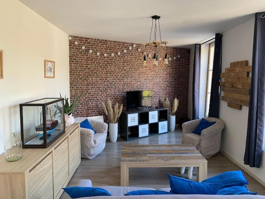 a living room with a table and a brick wall at La cabine d&#39;Amélie in Veules-les-Roses