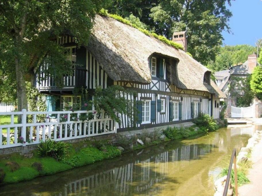 an old house with a thatched roof next to a river at La cabine d&#39;Amélie in Veules-les-Roses