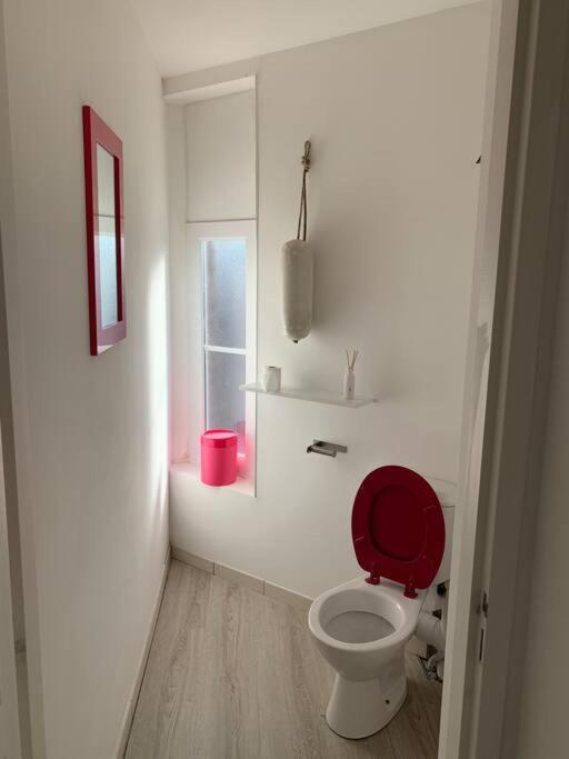 a bathroom with a red toilet and a window at La cabine d&#39;Amélie in Veules-les-Roses