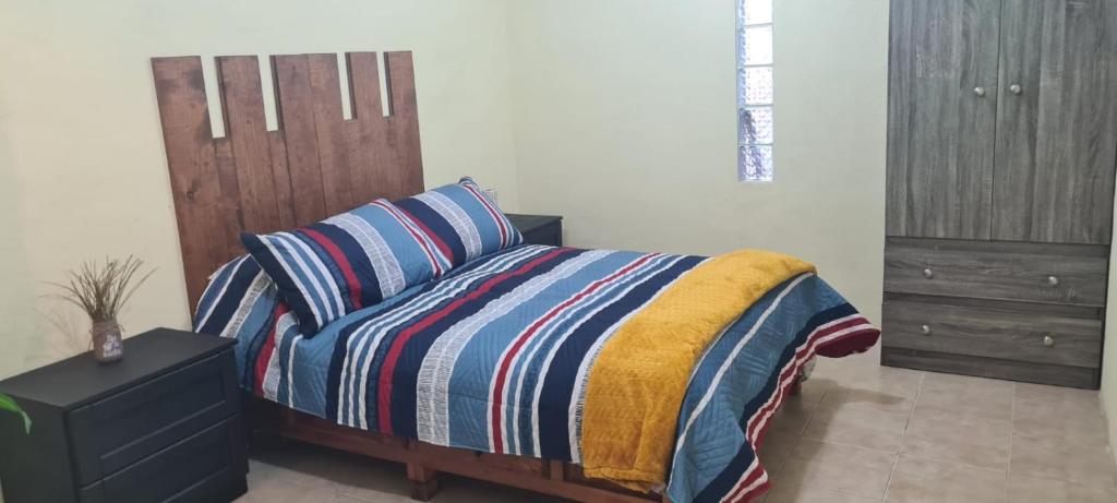 a bedroom with a bed with a striped blanket and a dresser at Hospedaje Real Ixiim Habitación (2) personas in Mineral del Monte