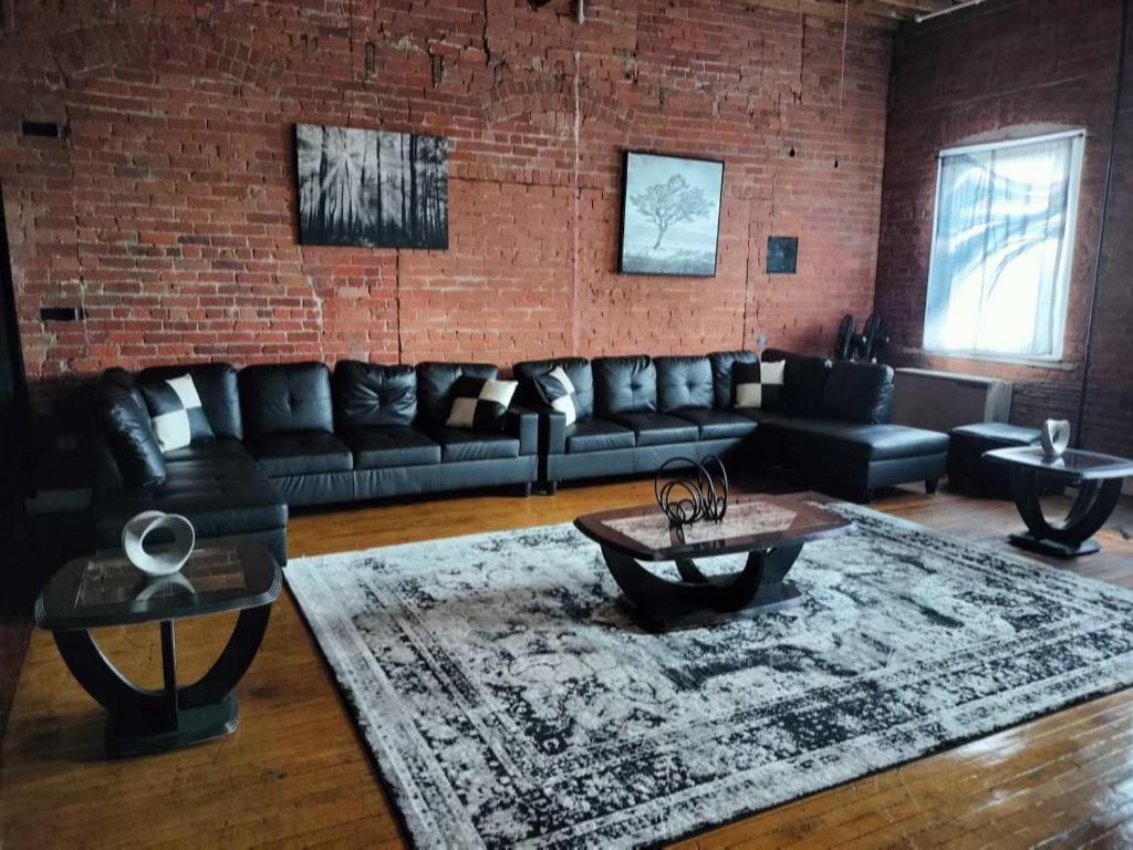 sala de estar con sofás de cuero y pared de ladrillo en FULLY EQUIPPED FOR THE 2024 NFL DRAFT!!! - Downtown Detroit Loft en Detroit
