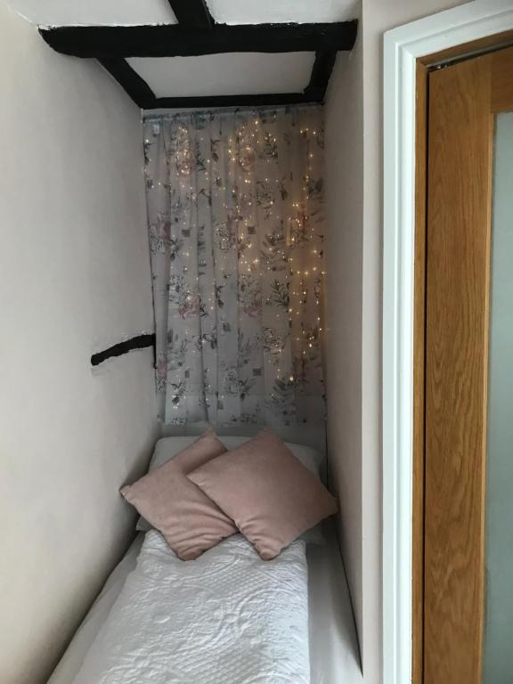 un piccolo letto con due cuscini in una stanza di Pipers Cottage - Quirky Cottage near Ironbridge! a Broseley