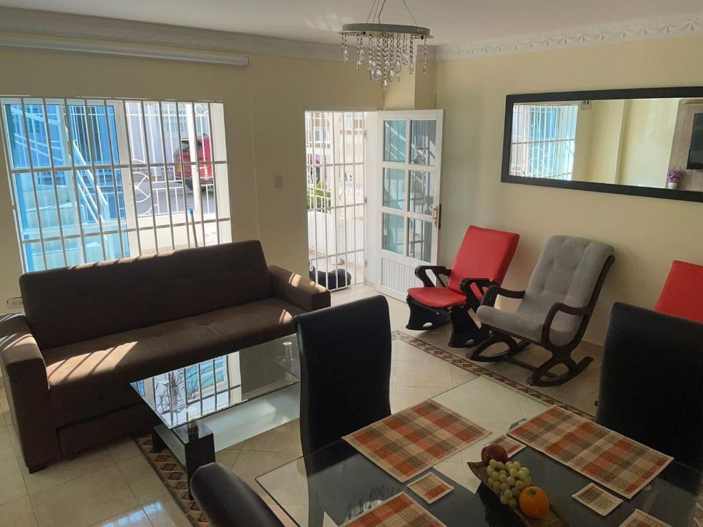 ein Wohnzimmer mit einem Sofa, Stühlen und Fenstern in der Unterkunft Apartamento 2 habitaciones in Barranquilla