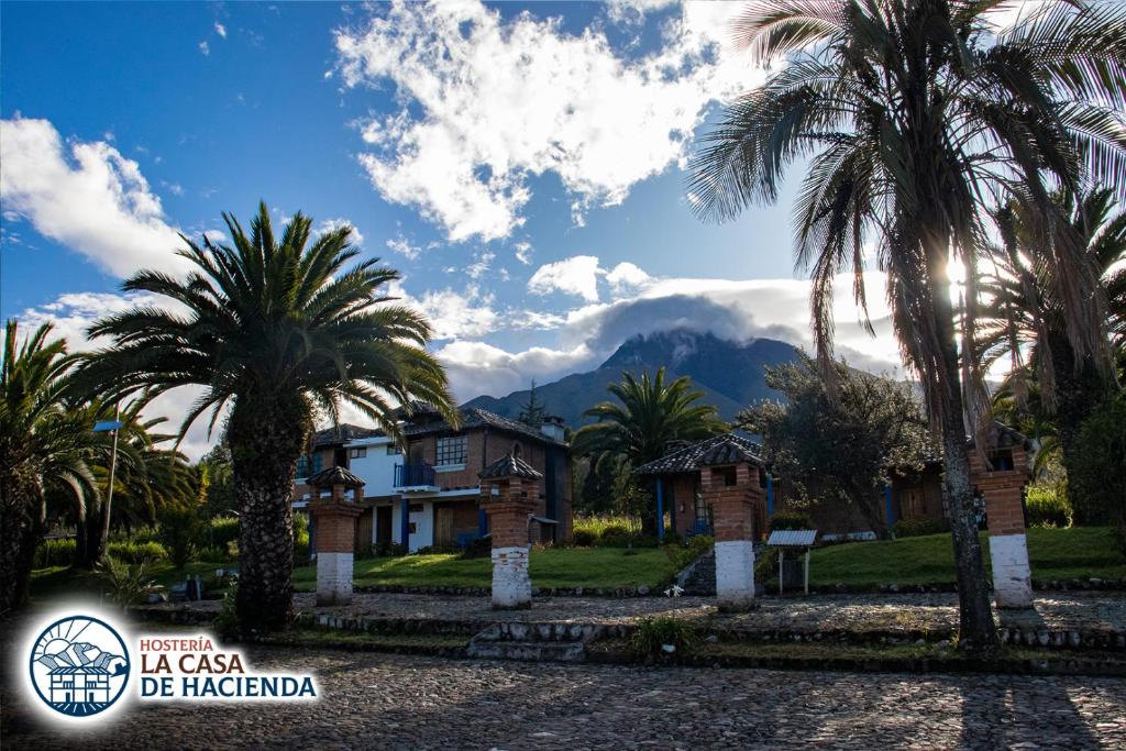 una casa con palmeras y montañas en el fondo en La Casa de Hacienda en Otavalo