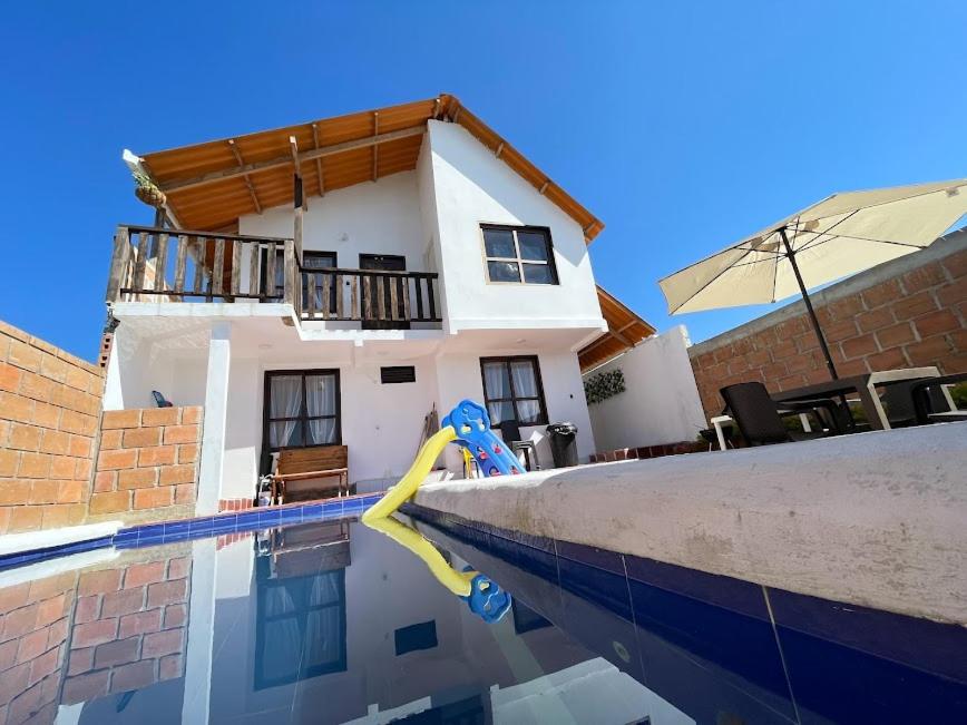 a house with a swimming pool in front of a house at Cabaña Hostal Santorini in Colón