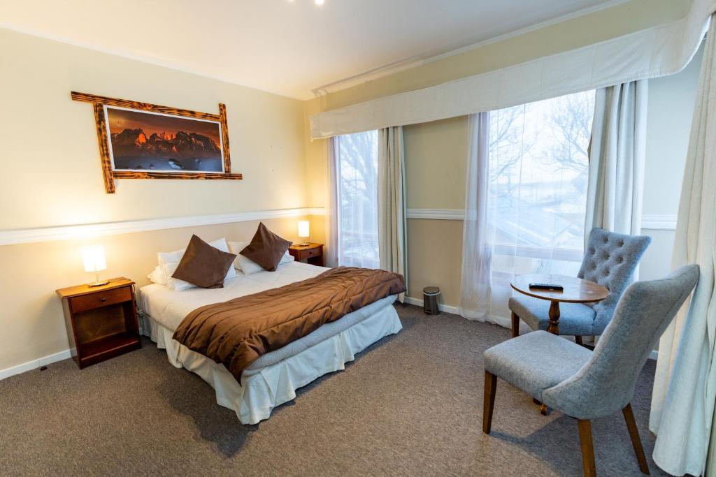 um quarto de hotel com uma cama e uma cadeira em Darwin Hotel em Puerto Natales