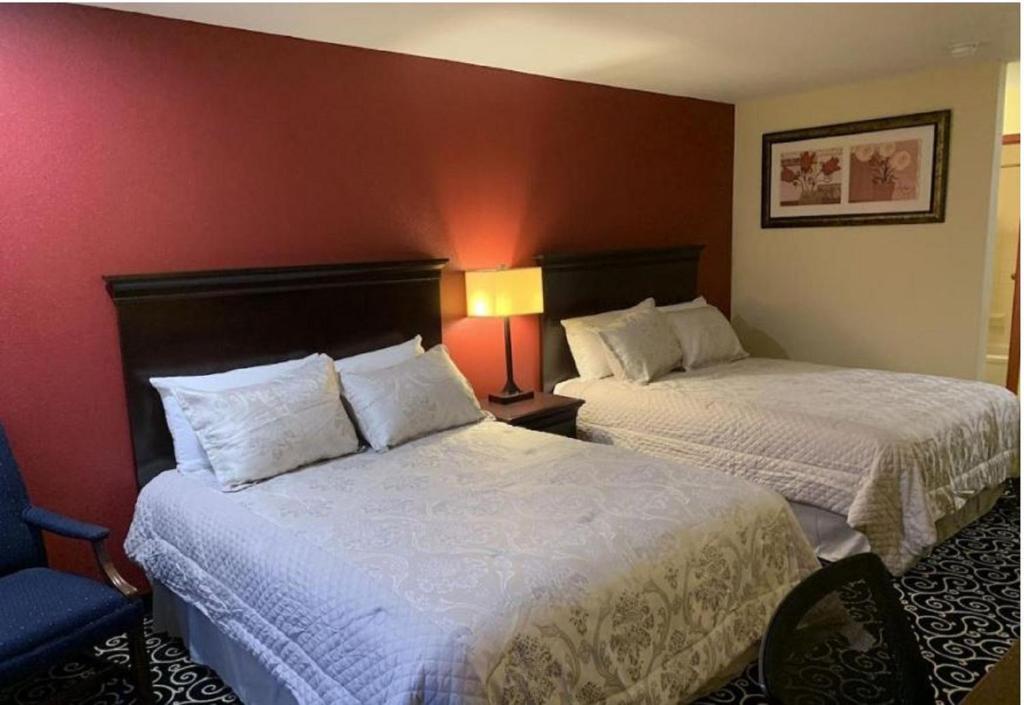 a hotel room with two beds and a chair at FairBridge Inn Express Hiawatha in Hiawatha