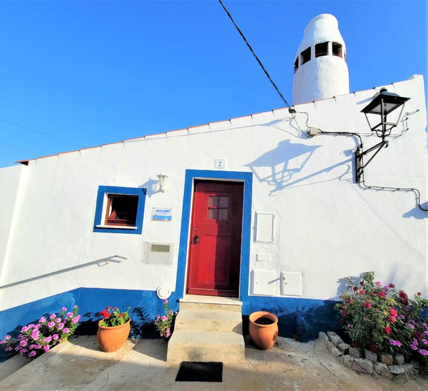 a red door on a white building with a lighthouse at Casa da Chaminé - Refúgio com Charme Alentejano in Amieira