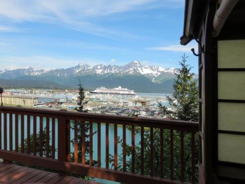 a balcony with a view of a cruise ship and mountains at A Cabin on the Cliff in Seward