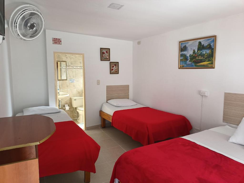 Habitación con 2 camas con sábanas rojas y mesa. en Hotel Mirador Plaza, en Pereira