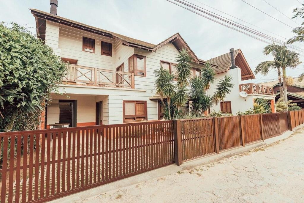 a wooden fence in front of a house at Acomodações Ibirawave in Barra de Ibiraquera