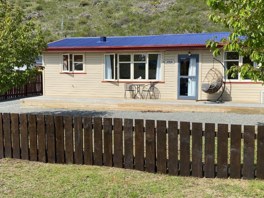 ein kleines Haus mit einem Zaun davor in der Unterkunft Cosy 1960's Kiwi Holiday House in Omarama