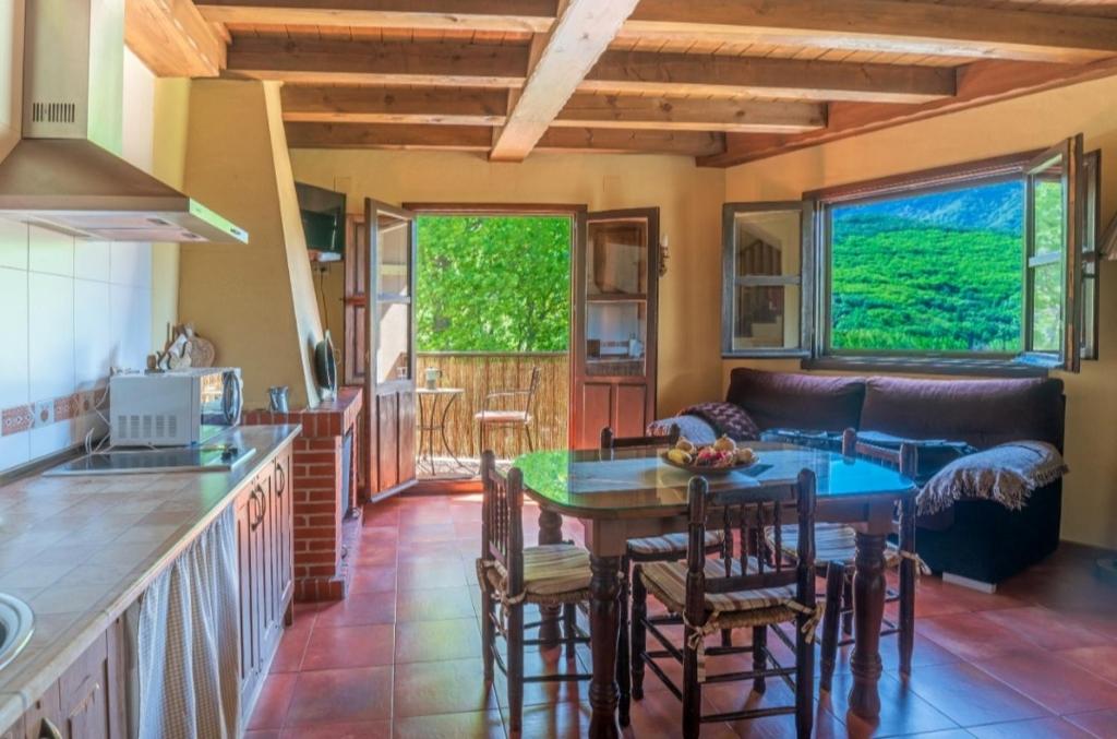 Una cocina y una sala de estar con mesa y sillas. en Complejo Rural Las Palomas, en Jerte