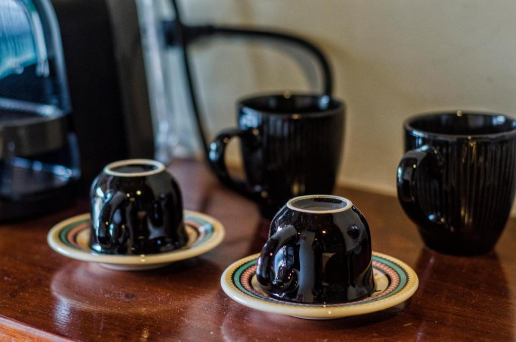 two black coffee mugs on a wooden table at Suítes O Pinhão e a Mantiqueira in Santo Antônio do Pinhal