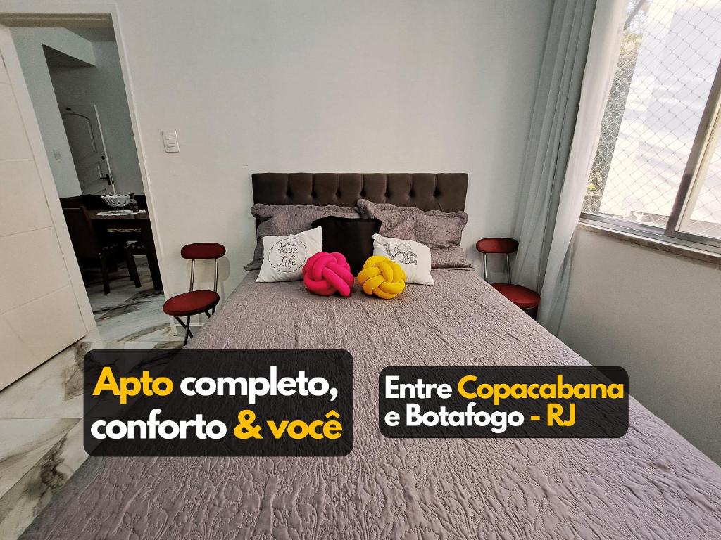 a bedroom with a bed with two colorful pillows at Estúdio completo entre Botafogo e Copacabana in Rio de Janeiro