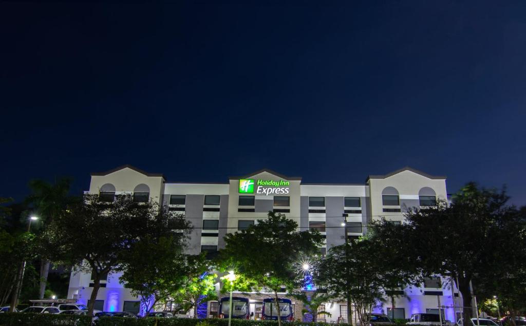 a hotel with a green sign on top of it at Holiday Inn Express and Suites Fort Lauderdale Airport West, an IHG Hotel in Davie