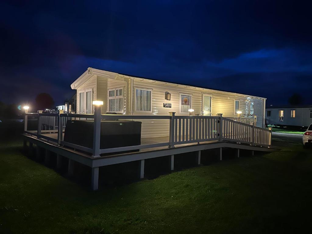 una casa móvil en un muelle por la noche en Seaside Heaven - Southerness Caravan Rental en Mainsriddle