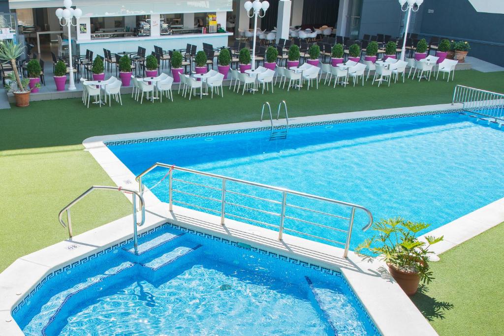 una gran piscina con sillas, mesas y sillas en Hotel Melina, en Benidorm