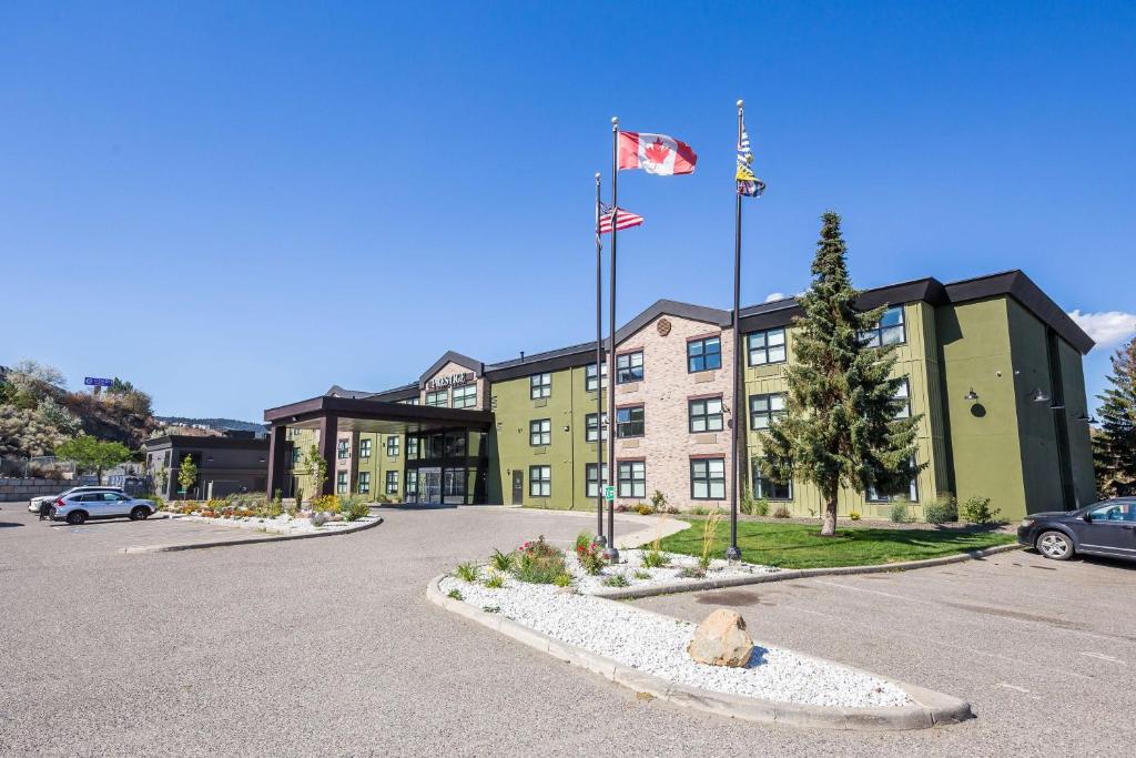 a building with two flags in a parking lot at Prestige Kamloops Hotel in Kamloops