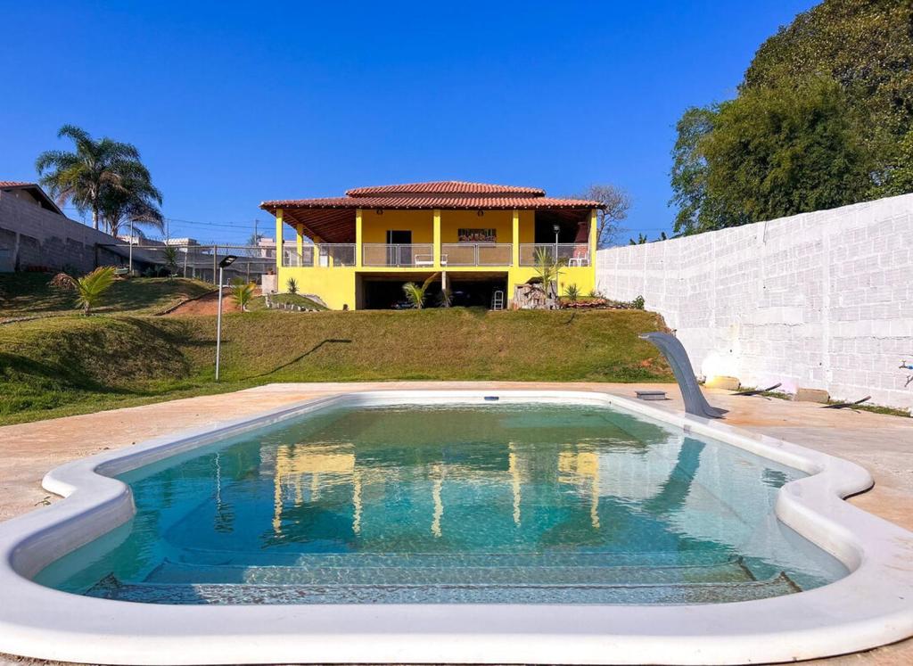 a house with a swimming pool in front of a house at Chacara com piscina, churrasq e WiFi em Taubate SP in Taubaté