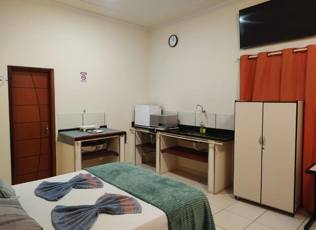 a kitchen with two beds and a desk in a room at Pousada Tamandaré in Campo Grande