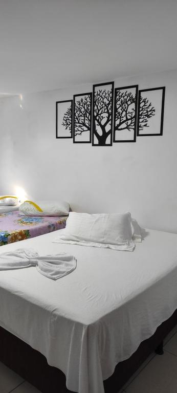 a white bed with four pictures on the wall at Pousada Ramon in Remígio