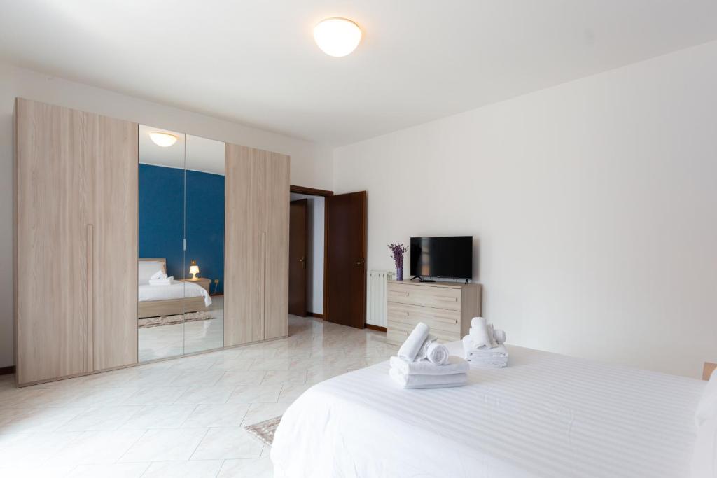 a white bedroom with a bed and a television at Carola's place - by Relais Di Giada in Como