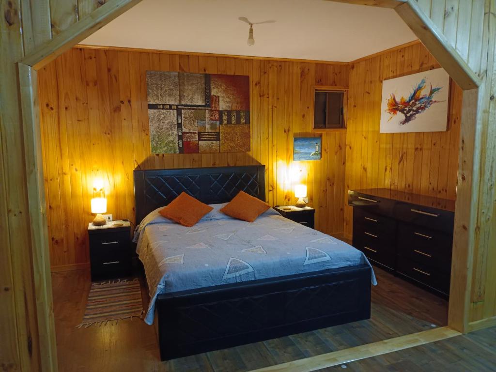 1 dormitorio con 1 cama con paredes de madera y suelo de madera en "Suite Dreams" Descanso Cerca del Mar, en El Quisco